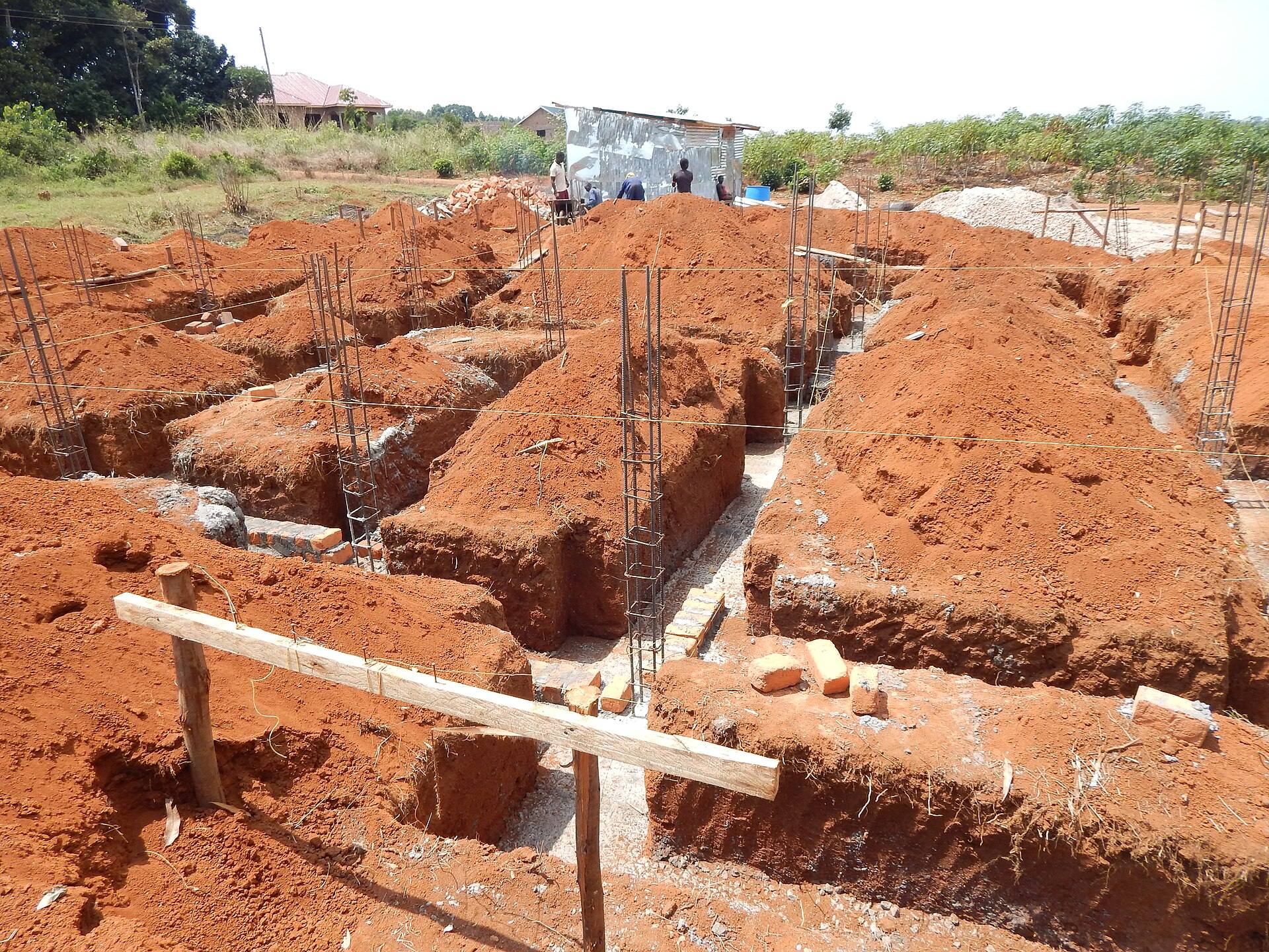 Trenches and steel reinforcement for building foundations dug into red earth